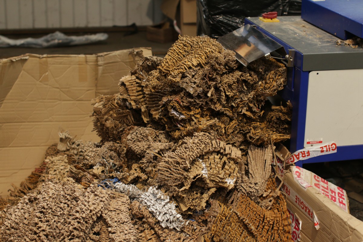 Shredded cardboard exiting a machine