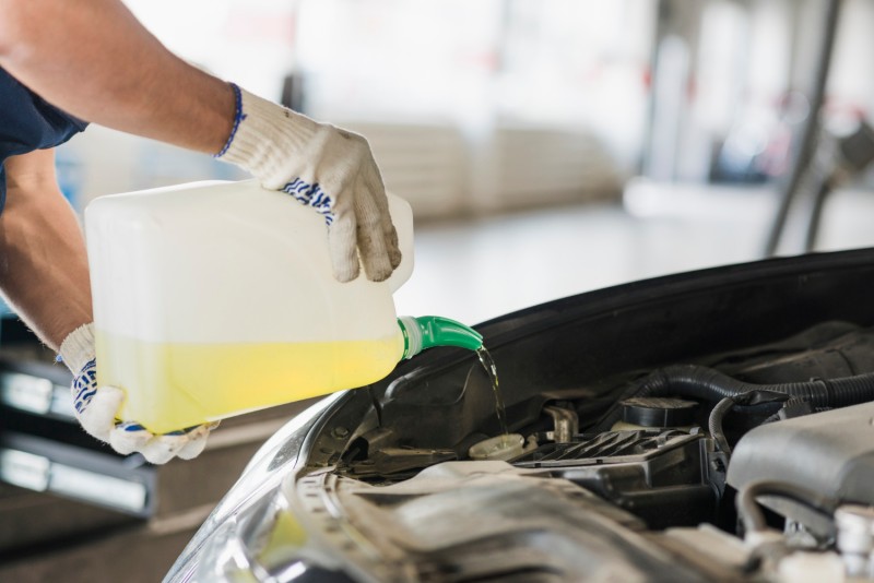 Car mechanic filling engine oil