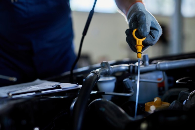 Car mechanic checking oil dipstick