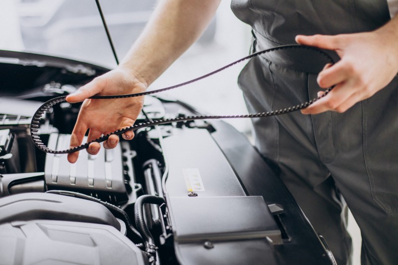 Mechanic holding car engine belt part