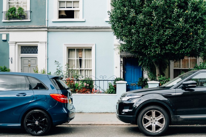 Two parked cars in front of terraced houses