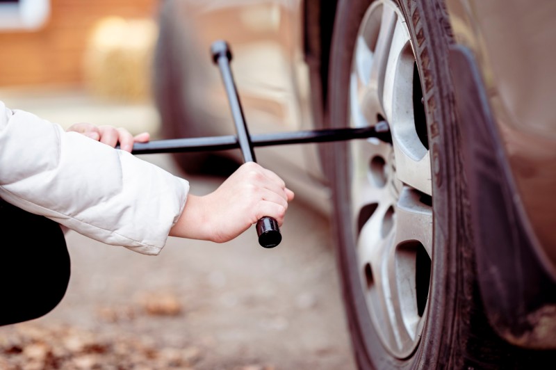 Woman using a tool on a car wheel