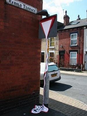 Upturned 'give way' triangle missing bottom segment made to look like a funnel flowing with white liquid, by unknown graffiti artist